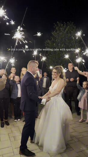 Wedding cake cut under an arch of sparklers